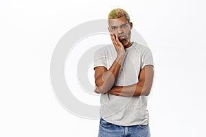 Man looks annoyed, bored or unamused, listens without interest, stands over white background