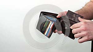 A man looks into an empty wallet without money  a wallet with credit cards. On white background.