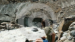 Man looks at the falling stones from the glacier. Rockfall in a tourist spot