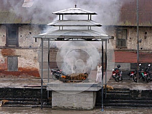 A man looks at a funeral pyre along the Bagmati River at the Pashupatinath temple in Kathmandu, Nepal