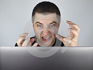 The man looks at the laptop, gets angry and annoyed about what he saw there. Expressing emotions and reacting to what you see on