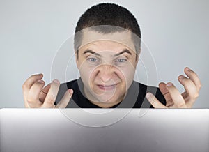 The man looks at the laptop, gets angry and annoyed about what he saw there. Expressing emotions and reacting to what you see on