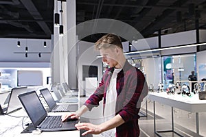 Man looks at laptops in the computer department at the technology store. Buy a laptop