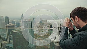 Man looks through magnifying device monocle at urban landscape of a large city