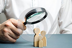 A man looks through a magnifying glass at a family figure. The study of family composition and demographic situation. Statistical photo