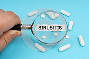 A man looks through a magnifying glass at pills and a leaf with the inscription - SINUSITIS