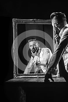 Man looks in the mirror. muscular macho man with athlete body near vintage mirror