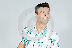 Man looks sideways and upwards. Handsome brazilian male wears summer clothes..