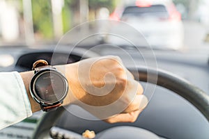 Man looks smartwatch showing time calories distance pedometer in car with traffic jam