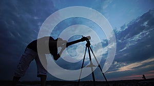 Man looks through a telescope at the evening sky