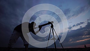 Man looks through a telescope at the evening sky