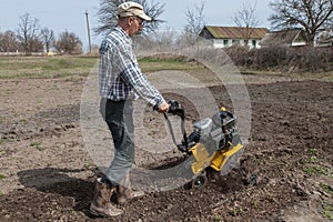 Man loosens the soil cultivator