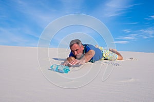 Man, lost in the desert reaches for the bottle of water