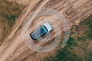 Man lost off-track on countryside road exiting out of the car and looking around, aerial shot from drone pov