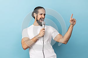 Man loudly singing song holding microphone in hand, having fun resting in karaoke singer performance