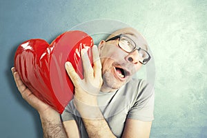 Man in love holds a red heart shape pillow