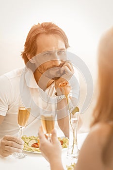 Man in love looks at his woman happily. Happy mature couple celebrating event or date at cafe on the sea coast outdoors