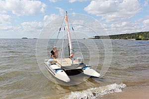 Man lowering catamaran into river,  Novosibirsk, Russia