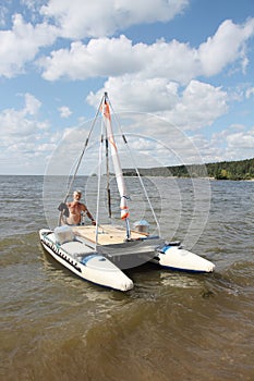 Man lowering catamaran into river, Novosibirsk, Russia