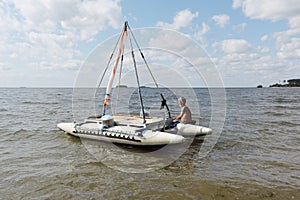 Man lowering catamaran into river, Novosibirsk, Russia