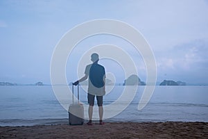 A man with luggage on the beach