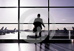 Man standing in airport, silhouette against glass wall