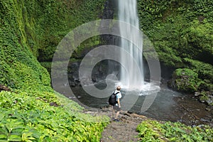 Man by lush green tropical Rain forest waterfall