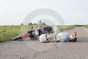 The man is lying on the asphalt near the motorcycle, the theme of road accidents