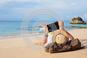 Man lying on the beach and using tablet