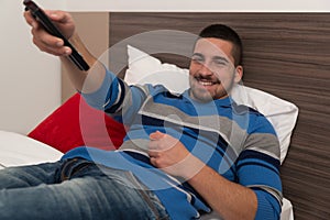 Man Lying On Bed And Holding Remote Control