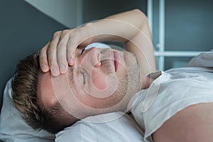 Man lying in bed at home suffering from headache or hangover photo