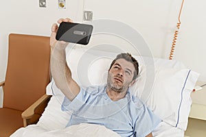 Man lying on bed hospital clinic holding mobile phone taking self portrait selfie photo sad depressed