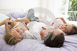 Man lying in bed with two young girls smiling