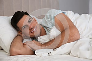 Man lying in bed with white linens at home