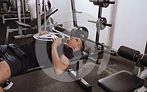 A man lying on a bench is preparing to lift weights by doing exercises during a workout. sports healthy lifestyle