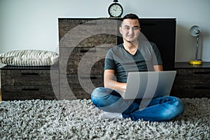 man lying on carpet while using laptop