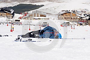 Man lying on cold snow after ski crash at Sierra Nevada resort in Spain with mountains