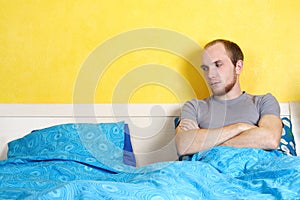 Man lying in double bed and looking on empty seat