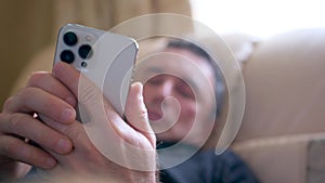 Man lying down on couch while looking at his cell phone alone at night