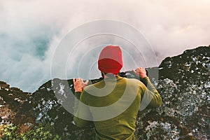 Man lying down on the edge cliff above clouds gaze into abyss