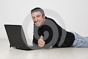 Man lying on floor with laptop and give thumbs