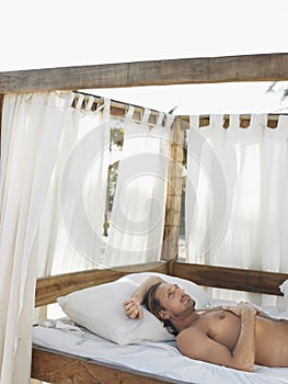 Man Lying In Four Poster Bed