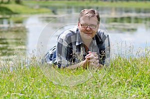 Man lying in grass on bank of pond