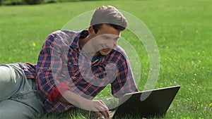Man lying on grass at park with laptop