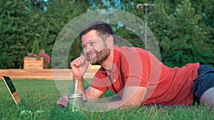 Man lying on grass and working on laptop