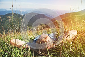 Man lying in high green grass on the mountain medaow