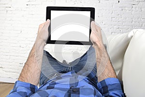 Man lying on home couch using digital tablet pad in portable internet technology