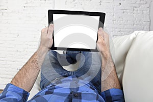 Man lying on home couch using digital tablet pad in portable internet technology