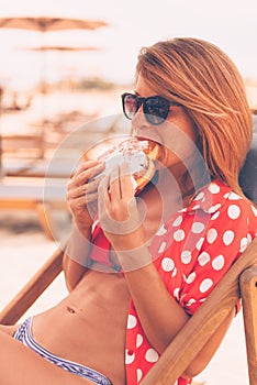 Young handsome woman eating doughnut