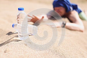 Man lying on sand in desert and feeling thirst